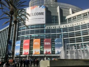 Picture of tall building called 'Anaheim Convention'. Building is many stories tall and primarily glass with steel support.