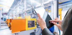 Woman tapping on tablet in machine facility