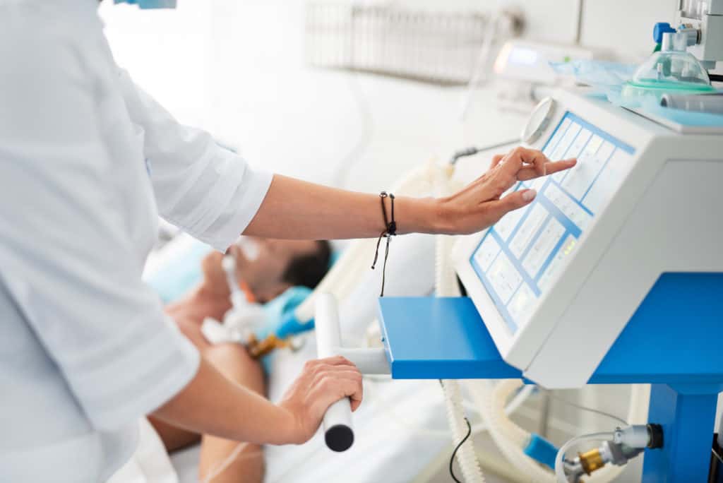 Female doctor touching monitor of mechanical ventilator