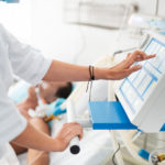 Female doctor touching monitor of mechanical ventilator