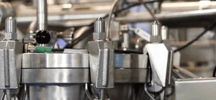 Close-up of industrial machinery with metallic parts and tubing, likely for processing or manufacturing.