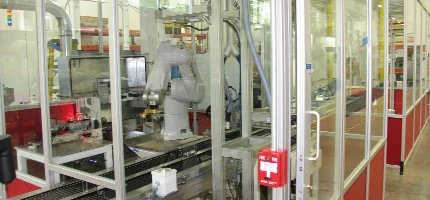 Industrial robot arm inside a safety caged area on a factory floor.
